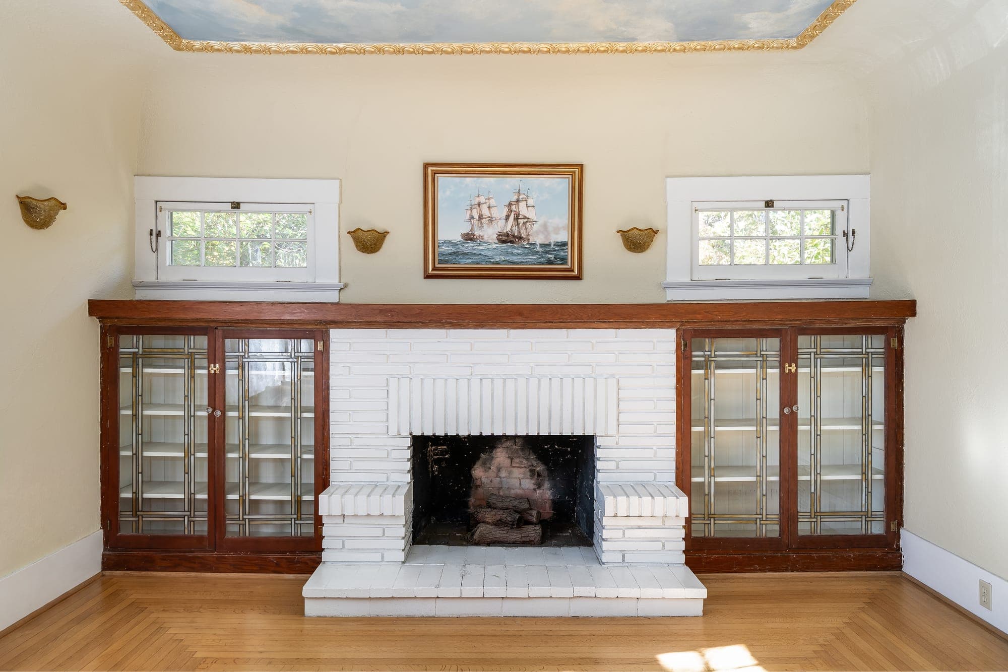 The white brick fireplace flanked by glass-front built-in cabinets.