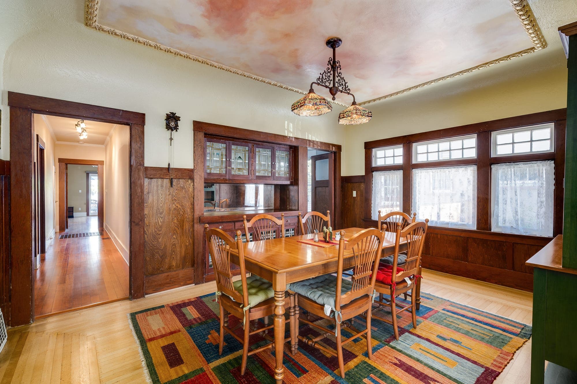 The dining room with wood wainscoting, a built-in buffet, and a wall of windows.
