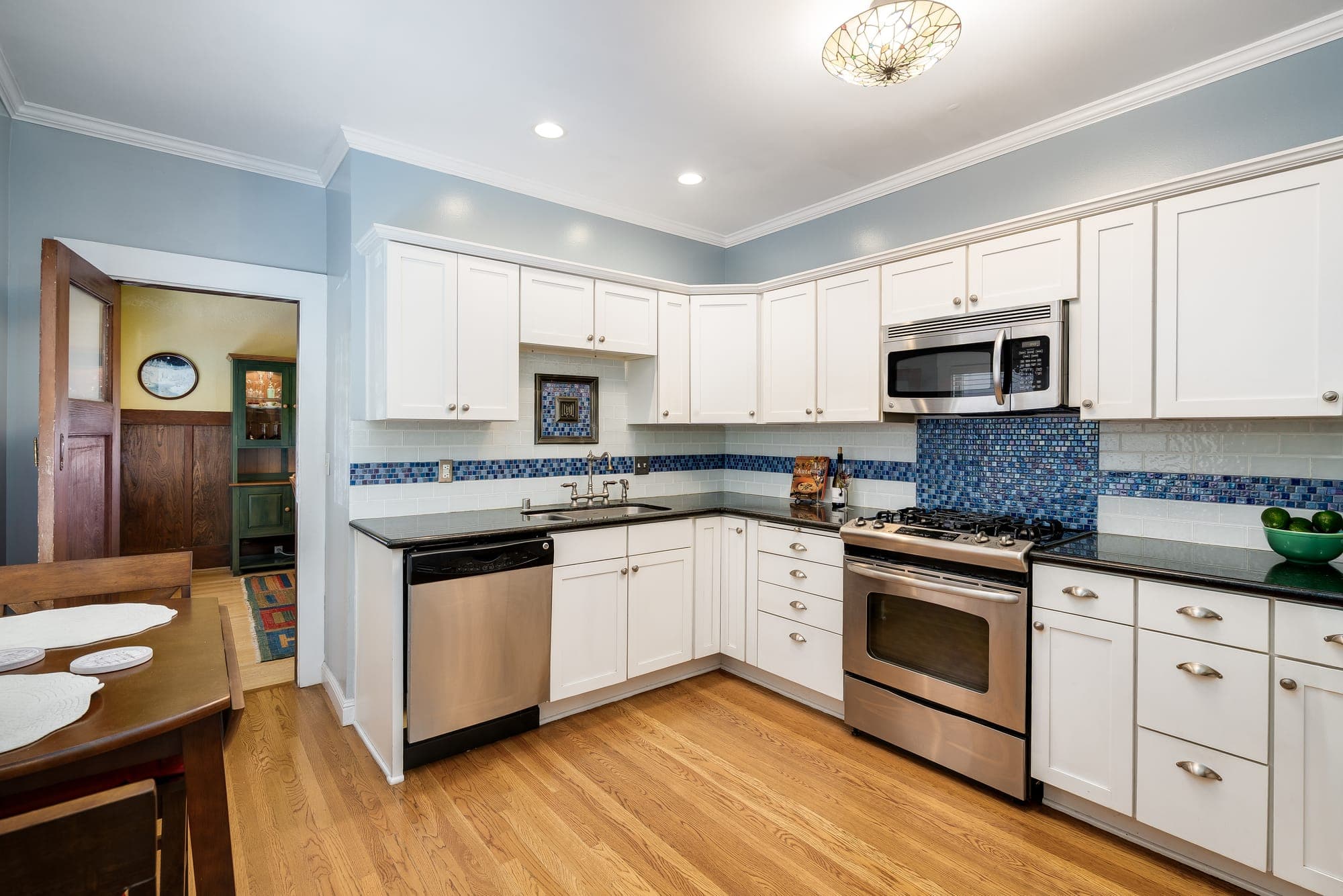 The kitchen with white cabinetry, stainless appliances, and a tiled backsplash.