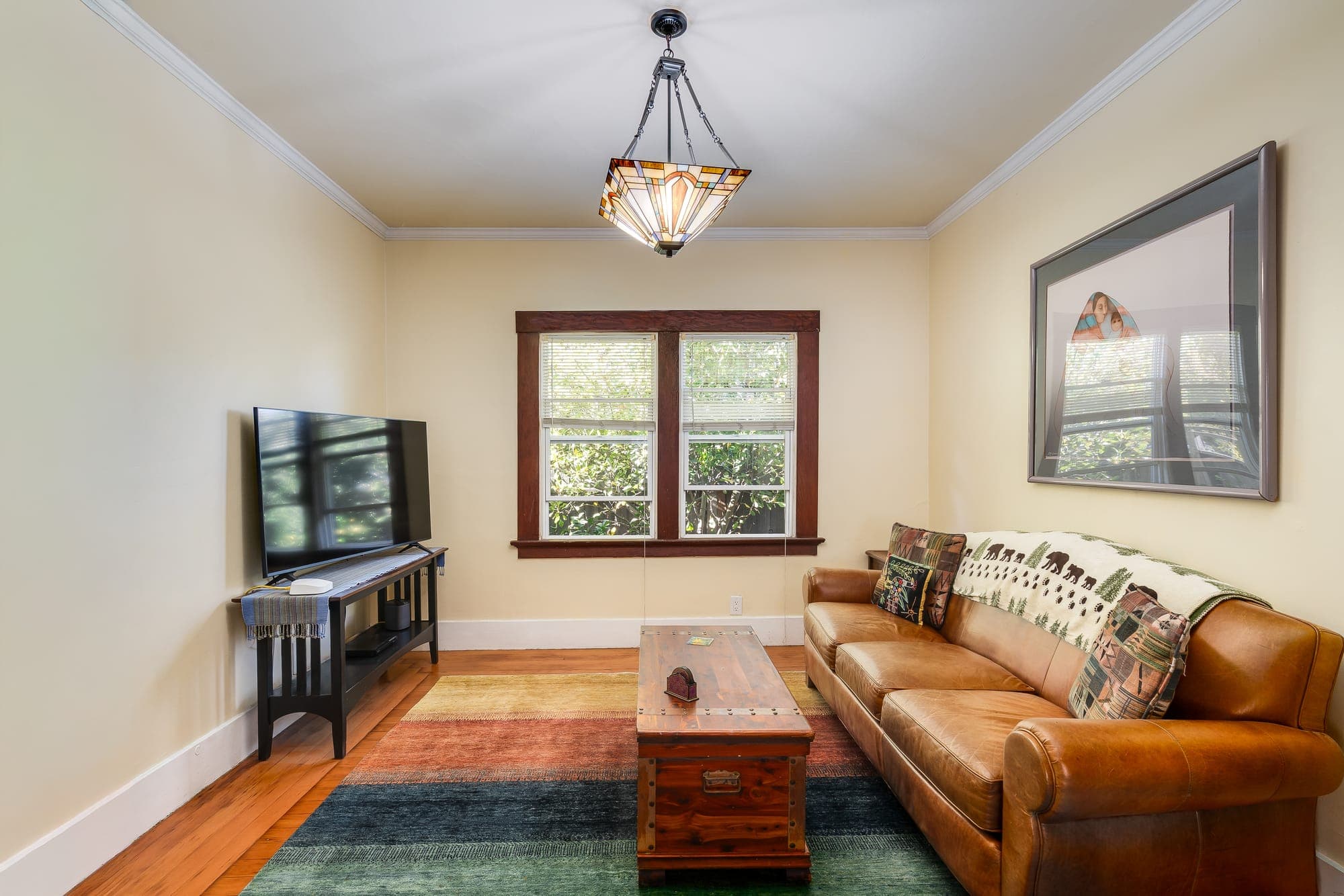 A den with a window to the garden and a sofa facing the media wall.