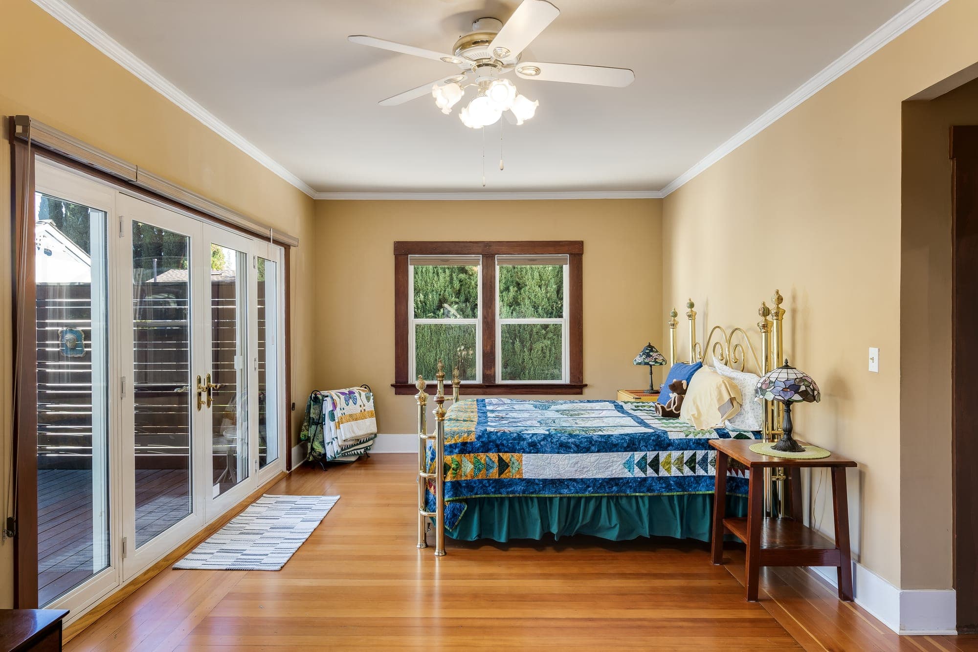 A bedroom with French doors to the rear deck and windows on two sides.