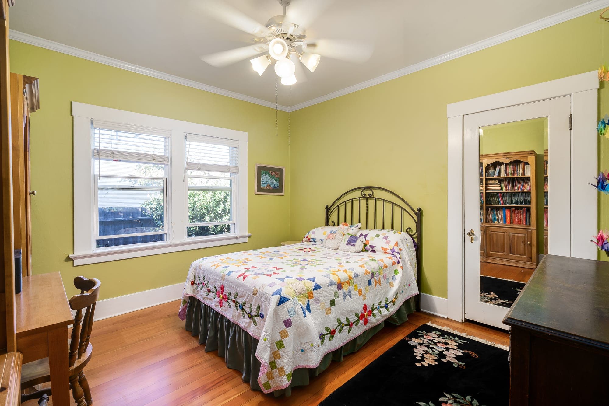 A bedroom with a double window and a mirrored door.