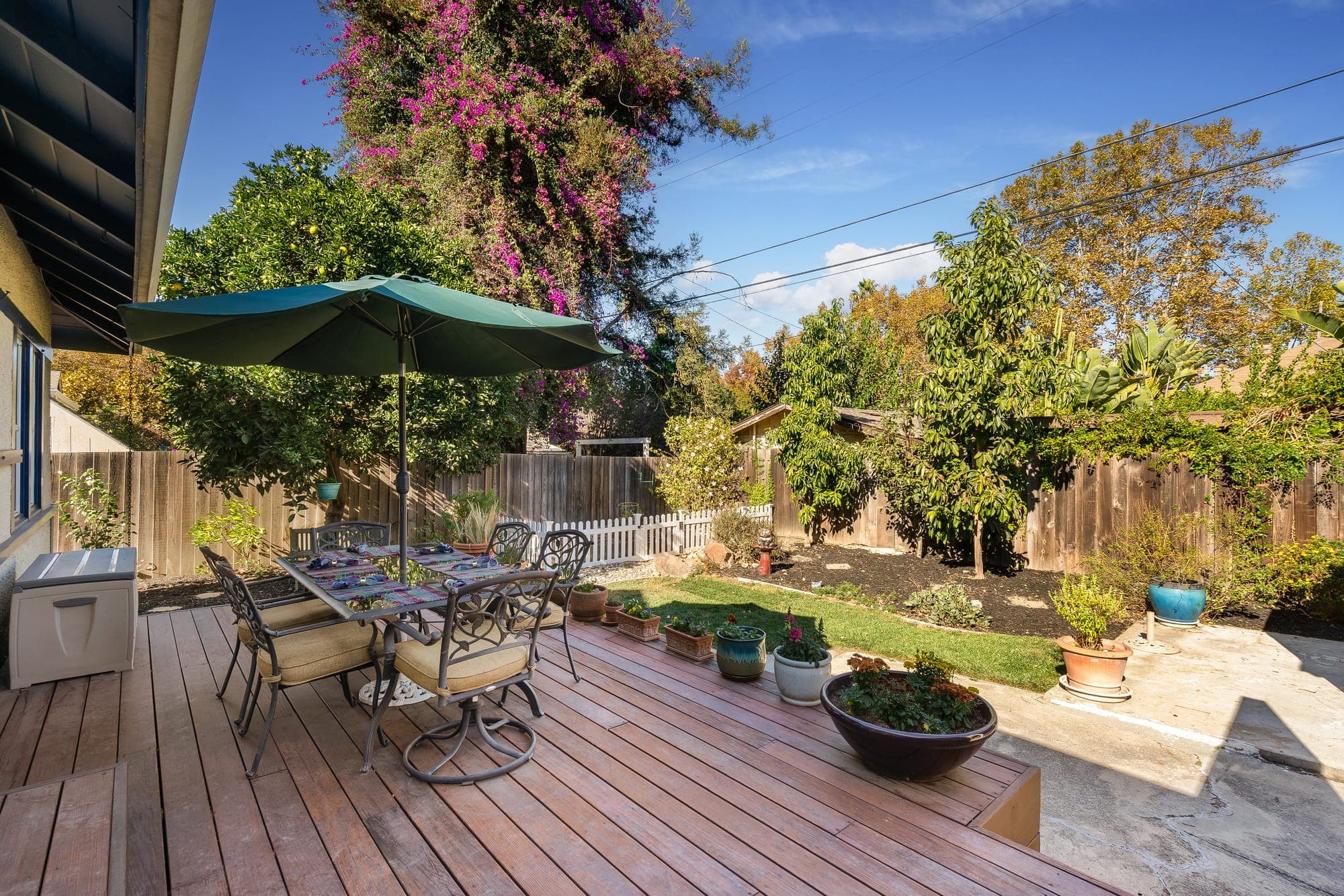 The rear deck with an umbrella-shaded dining table beside the garden.