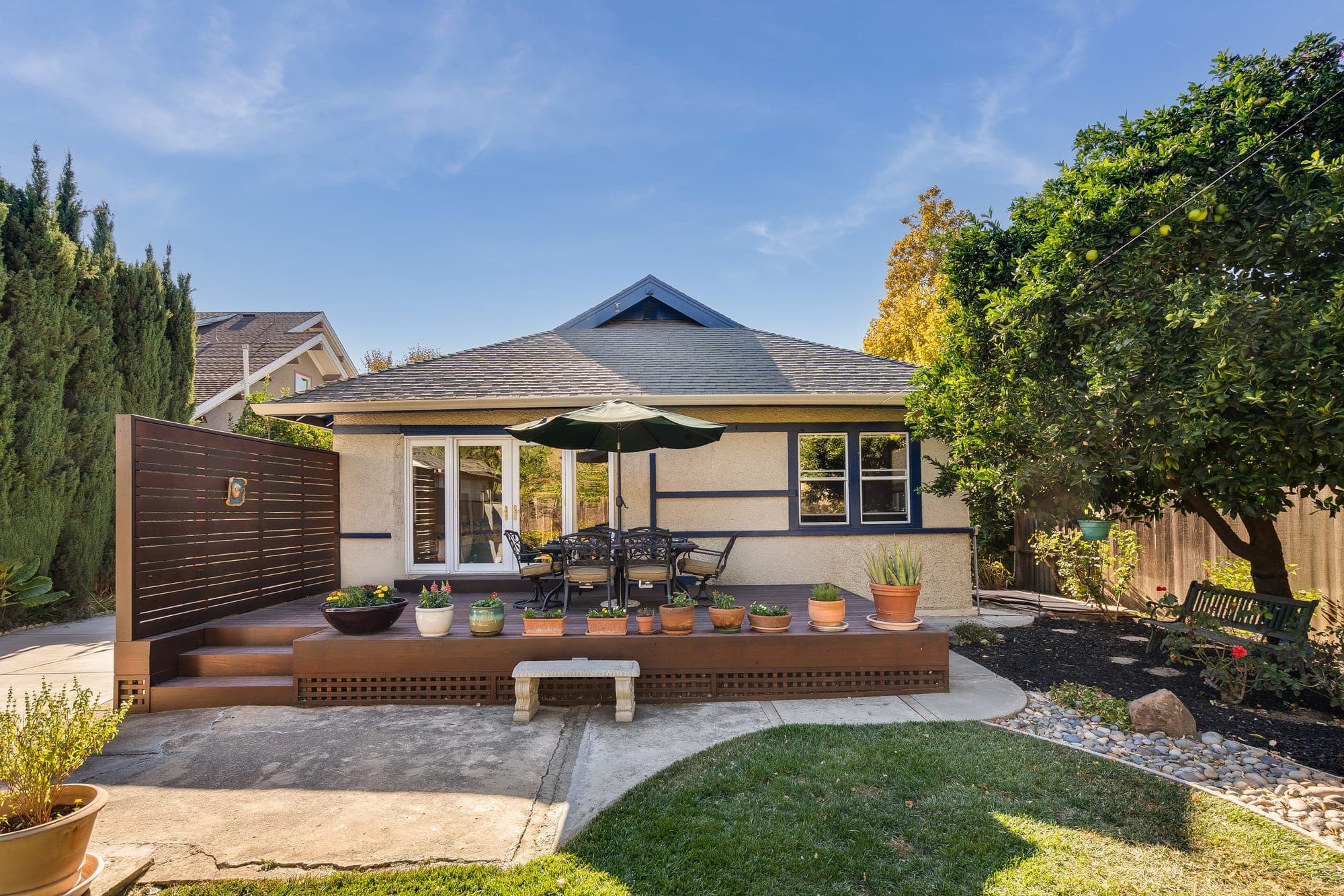 The back of the home across the lawn, with the deck and privacy screen.
