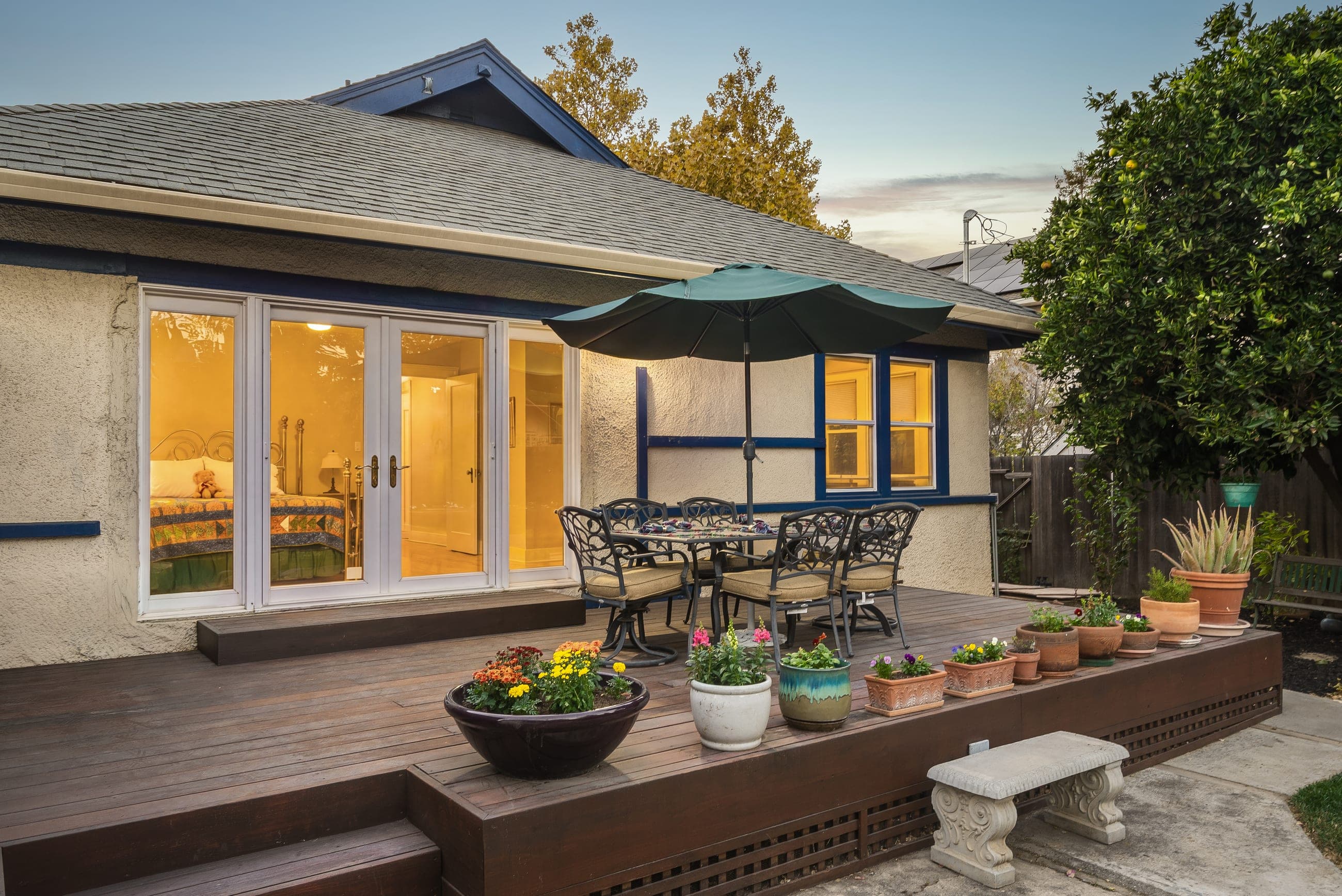 The rear deck at twilight, French doors open to the lit interior.
