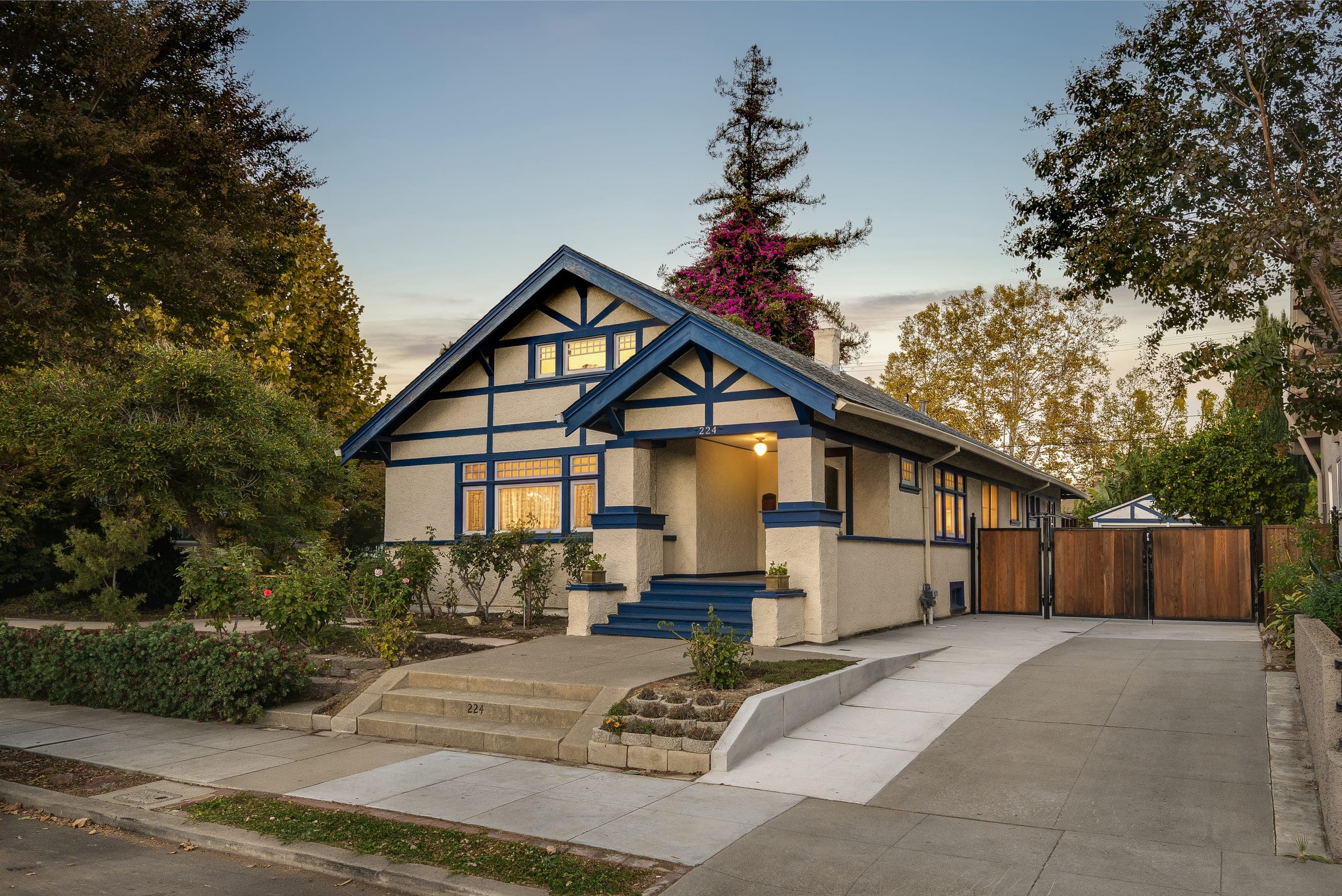 224 S 14th Street at twilight: a Craftsman bungalow with twin gables, blue trim, and glowing windows.